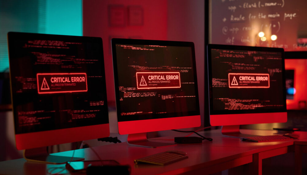 Background image of three computer monitors with emergency messages on screen in red lights copy space by Media_Photos