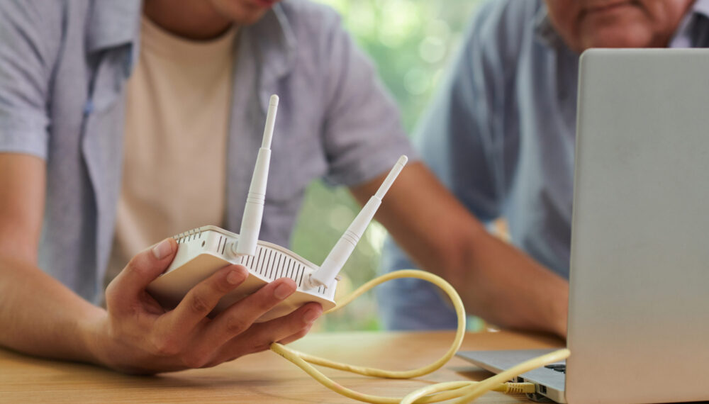 Young man installing wi-fi router in home of his father by DragonImages